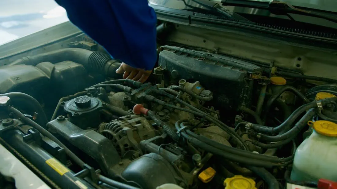 Meccanico in tuta da lavoro mentre controlla il vano motore di un'auto in officina a Milano