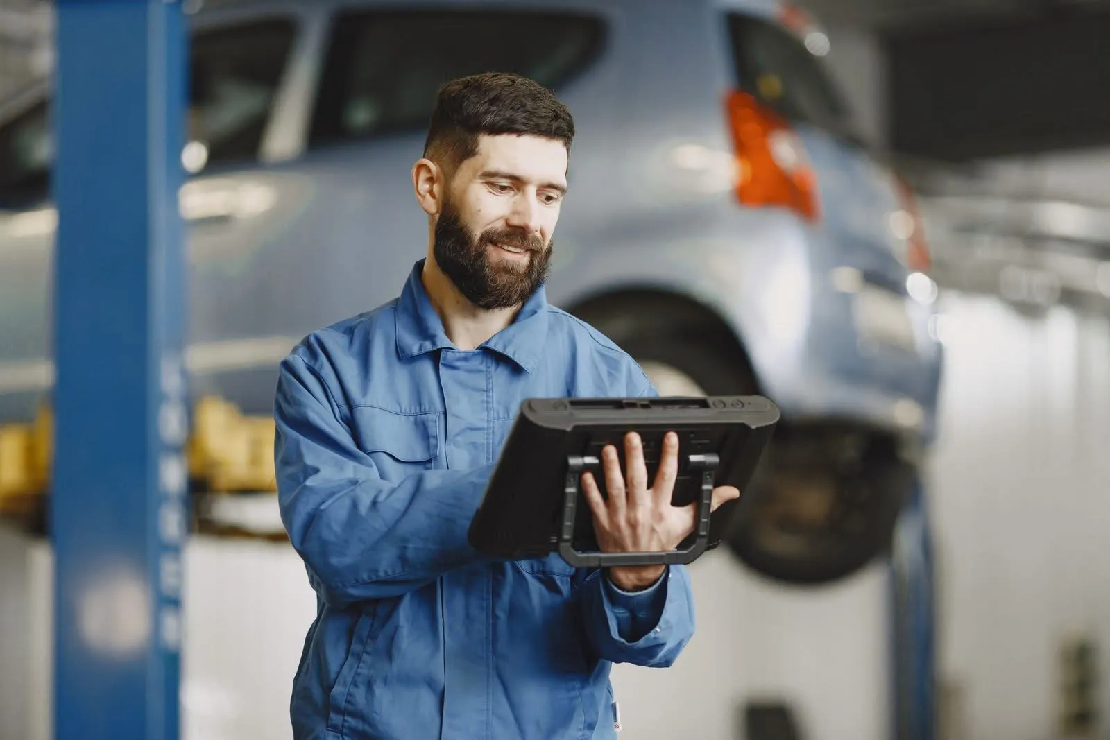 Tecnico controlla i valori di pressione e sensori con il tester davanti all'auto sul ponte
